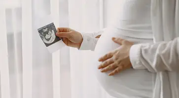https://ognikubani.ru/wp-content/uploads/2023/02/pregnant-woman-standing-by-the-window-looking-at-a-photo_1
