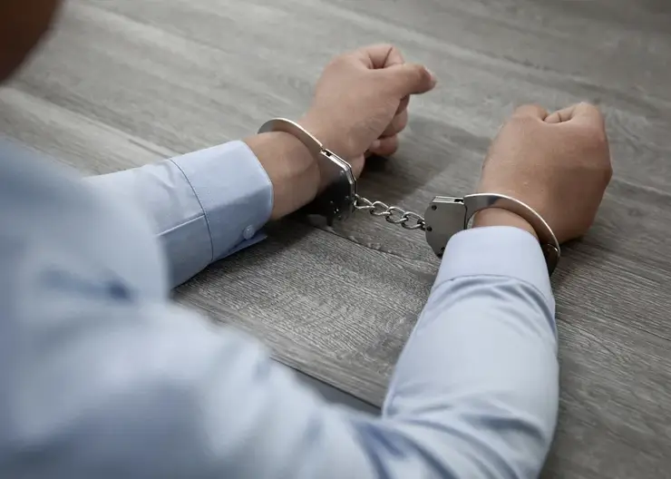 selective-focus-shot-male-hands-handcuffs-wooden-table