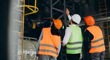 three-factory-workers-safety-hats-discussing-manufacture-plan