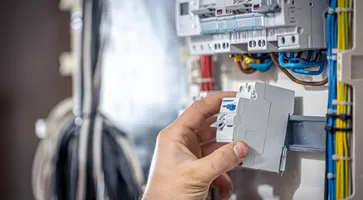 male-electrician-works-switchboard-with-electrical-connecting-cable