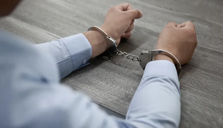 selective-focus-shot-male-hands-handcuffs-wooden-table