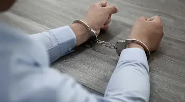 selective-focus-shot-male-hands-handcuffs-wooden-table
